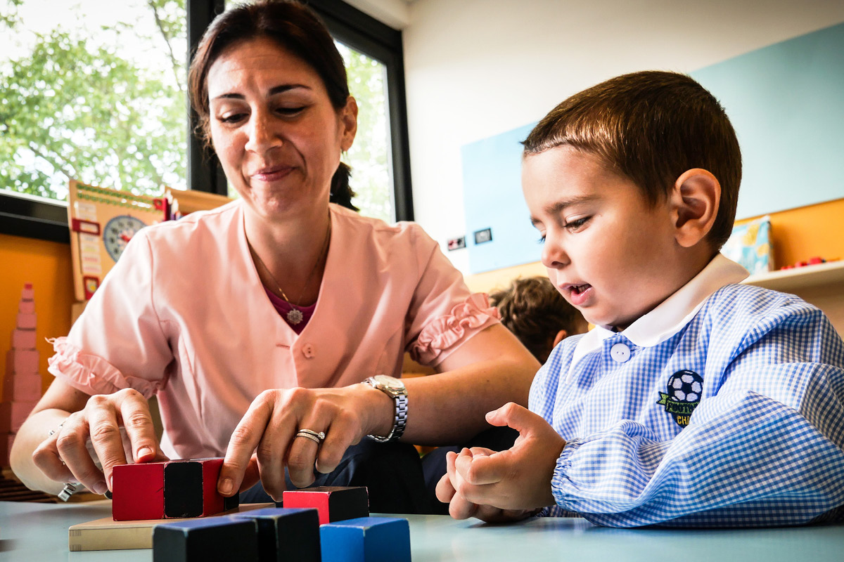 Educatrice sorridente mostra un'attivit&agrave; a un bambino a scuola