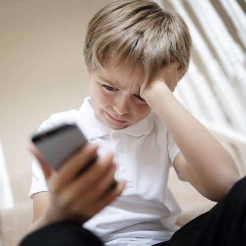 Ragazzo preoccupato che impugna uno smartphone-cyberbullismo